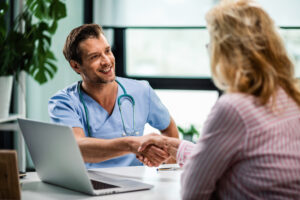 happy-doctor-shaking-hands-with-wife-his-senior-patient-medical-clinic