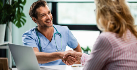 happy-doctor-shaking-hands-with-wife-his-senior-patient-medical-clinic